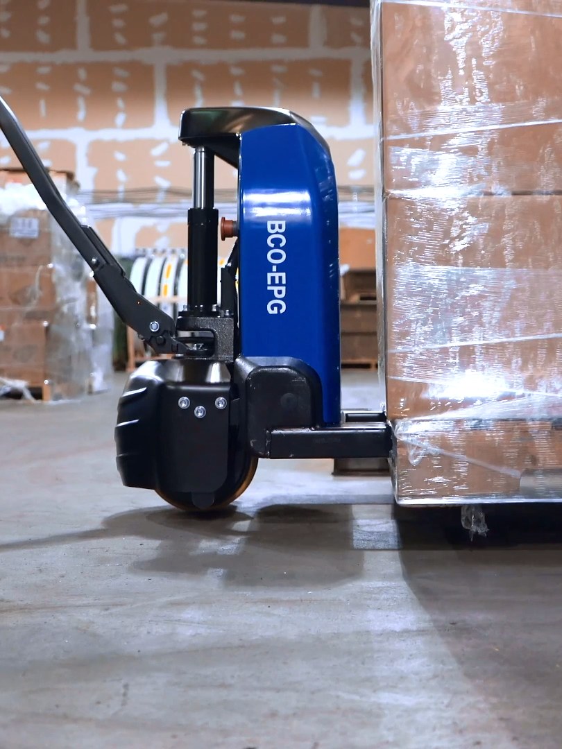 Electric pallet jack in a dark studio, its BCO-EPG cover and red lights up close