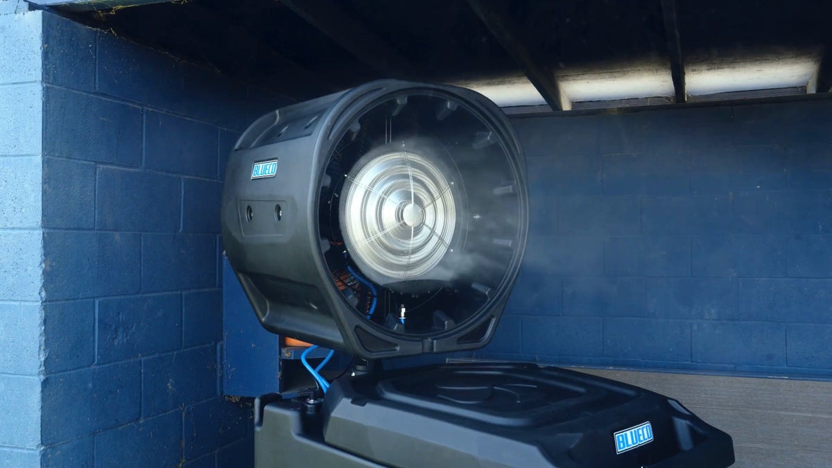 HydroBlu misting fan head spraying a fine mist in front of a blue block wall