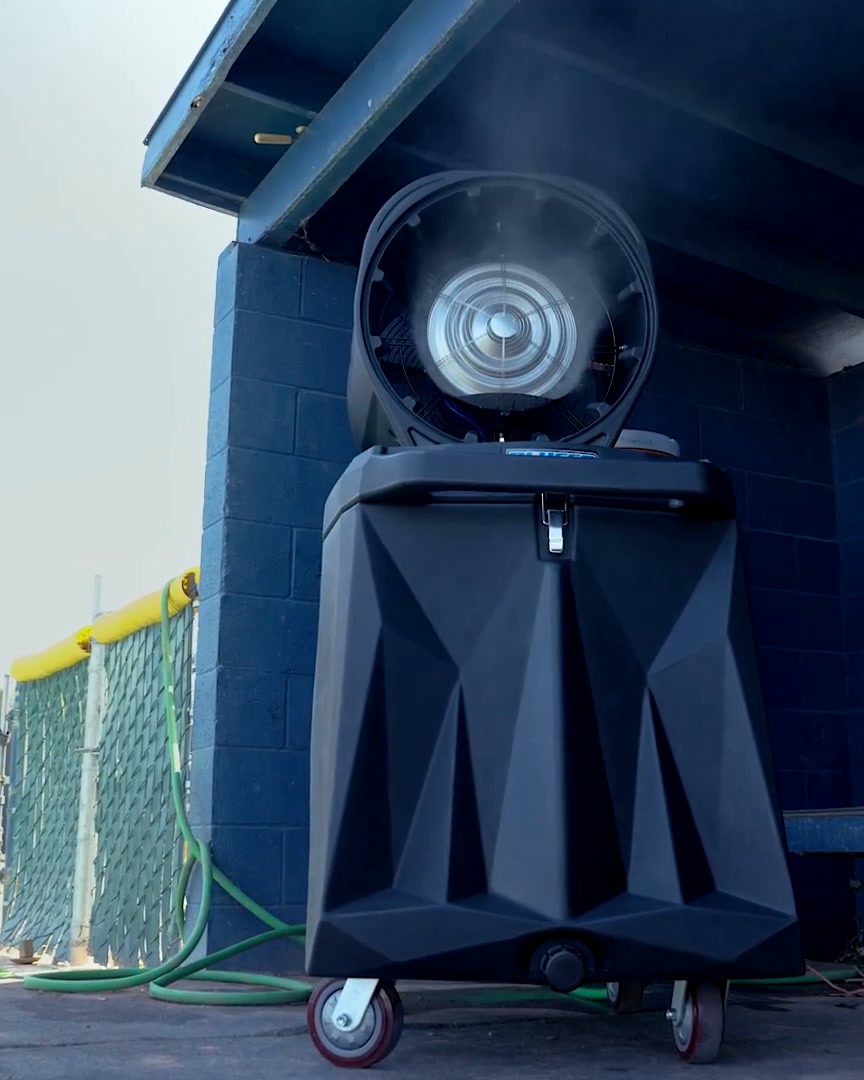 HydroBlu misting fan on its tank, misting outdoors beside a painted block wall