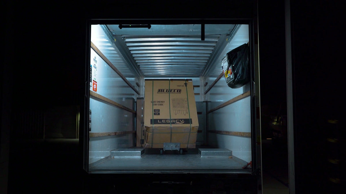 Box truck interior lit by a work light, with a boxed cooler inside